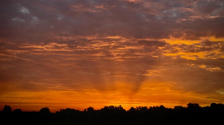 Bewölkter Himmel kurz vor Sonnenaufgang in leuchtend orangenen Farben